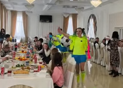 Аніматори у футбольних костюмах розважають дітей різного віку за святковим столом