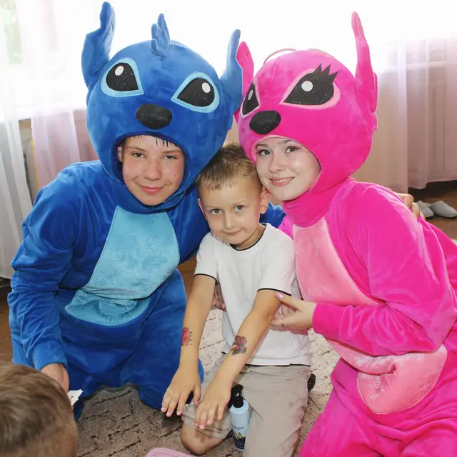 Аніматори Стіч та Енджел з дитиною на святі